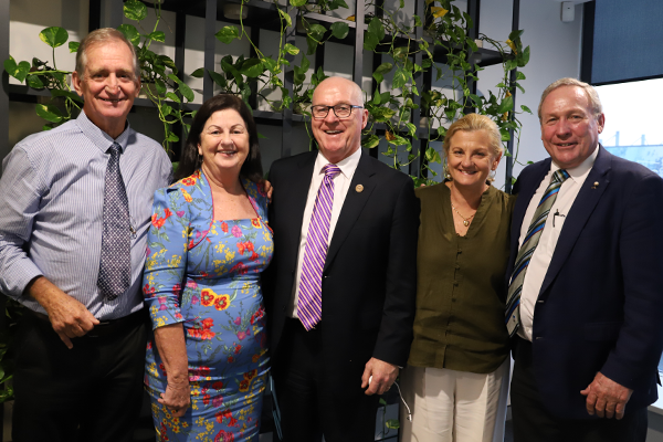 Retiring Policy Executive members smile for a photo in front of a vertical plant wall