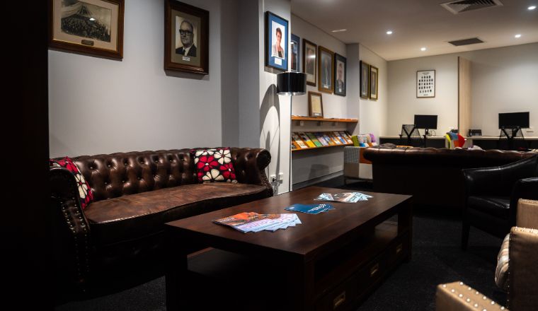 The Members' Lounge at LG House with dark wooden tables, Chesterfield sofas and portraits lining the walls. 
