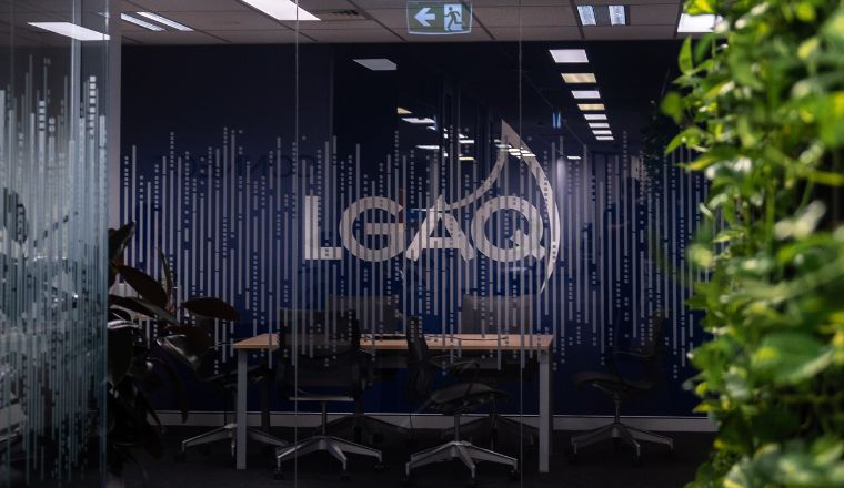 A meeting room in LG House with glass exterior wall showing the dark blue wall with LGAQ logo. Greenery from indoor plants are on the right. 