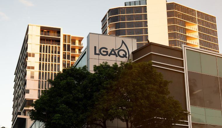 View from Evelyn Street, Newstead, looking up at the 'new' LG House building. The LGAQ logo stands out above trees and tall apartment buildings are in the background. 