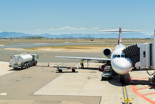 A plane sitting at an airport with a fuel truck near by