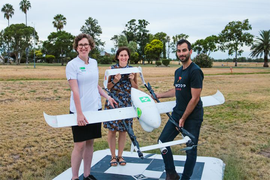 Residents stand with an autonomous drone in a field